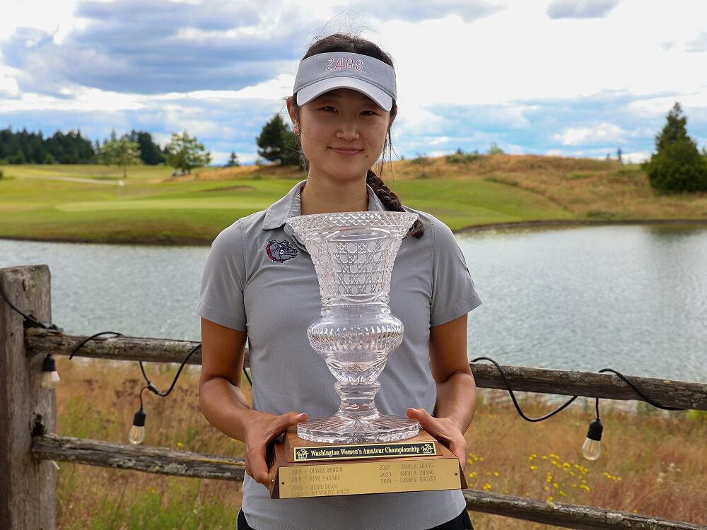 Golfer poses with the Washington Women’s Amateur Championship trophy on the golf course.