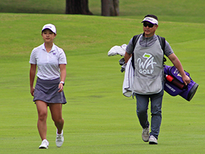 Brittany Kwon strolls down the fairway with her caddie in tow.