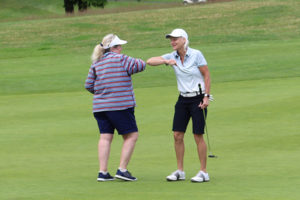 Two women tapping their elbows at the end of a round of golf